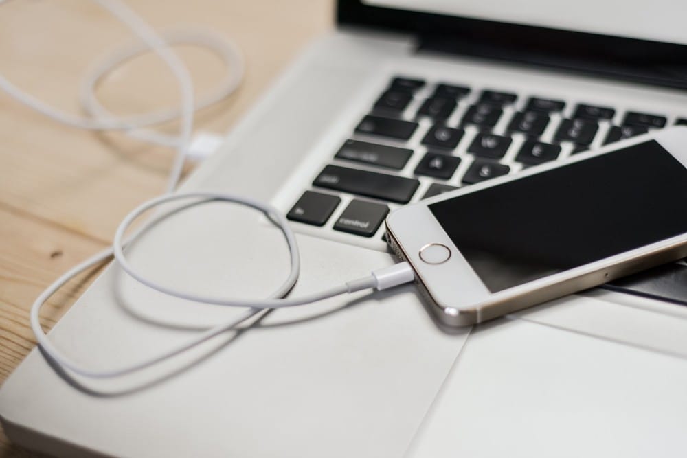 Adaptador enchufe Australia móvil de apple cargándose y conectado a un ordenador Mac